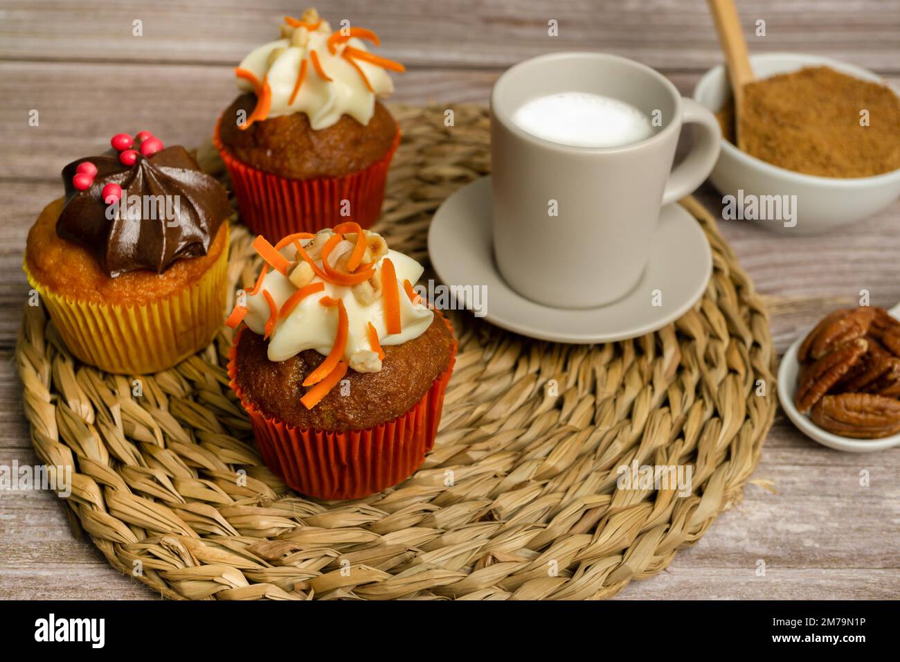 Auswahl an Schokolade-, Sahne- und Karotten-Cupcakes mit verschiedenen Hintergründen Stockfoto
