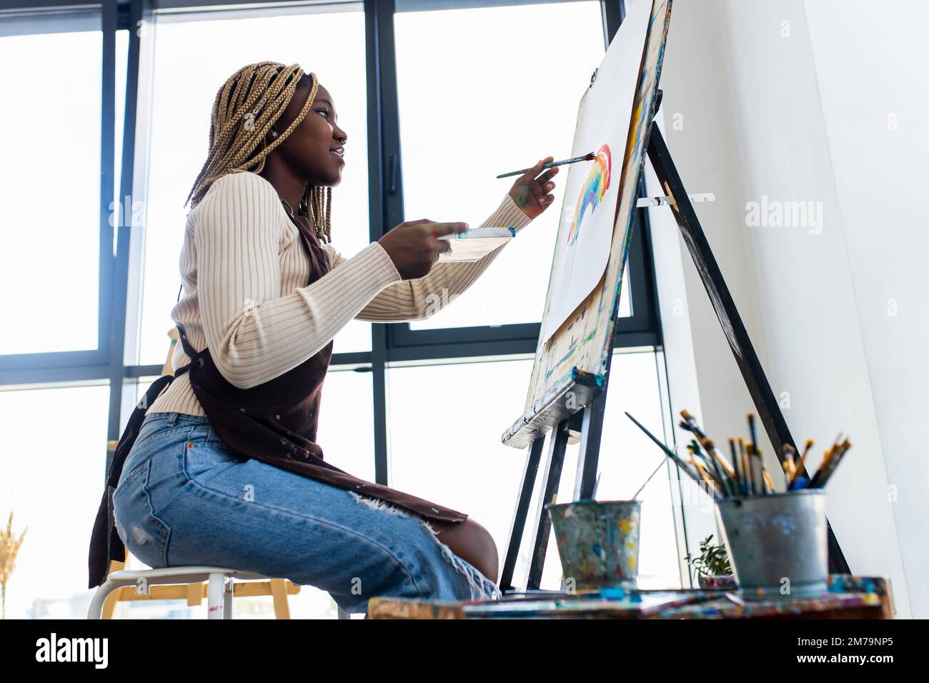 brasilianische Frau mit Dreadlocks in weißer Bluse im Kunststudio Stockfoto