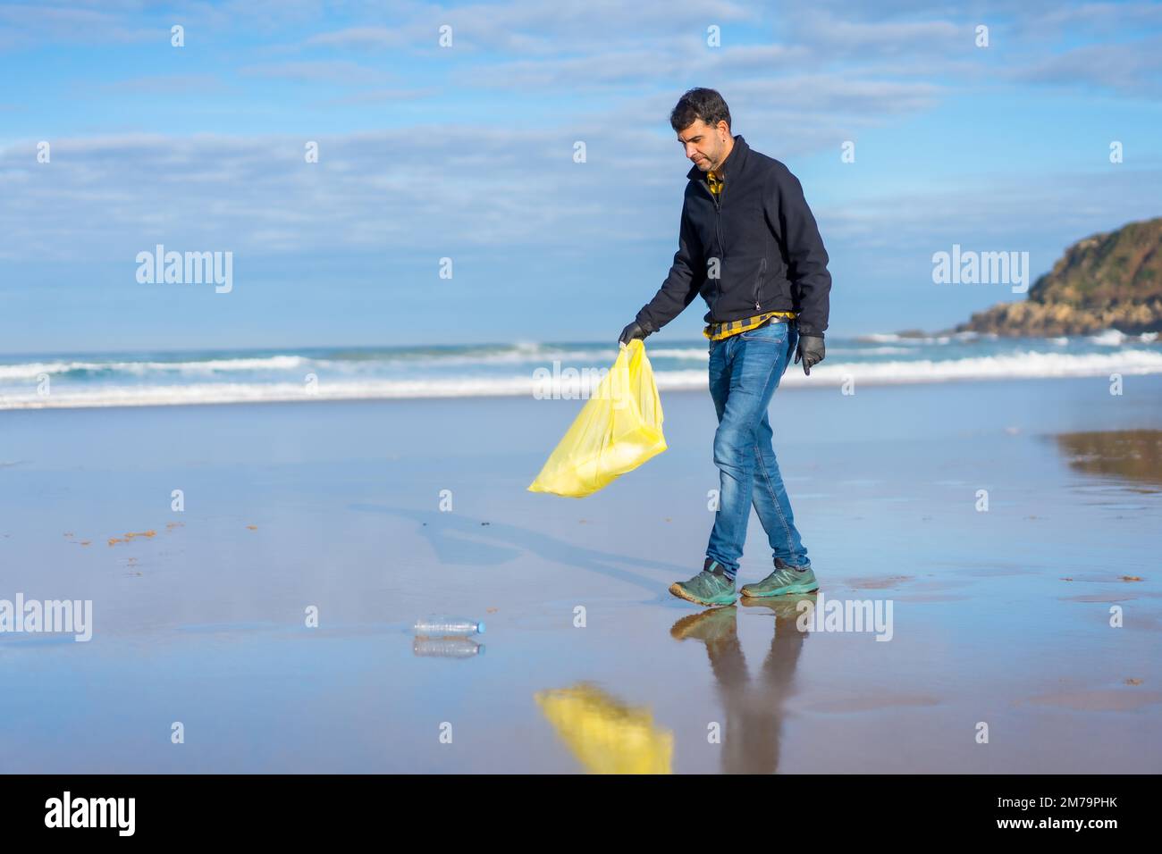 Mann, der Müll oder Plastik am Strand sammelt. Ökologiekonzept, Meeresverschmutzung Stockfoto