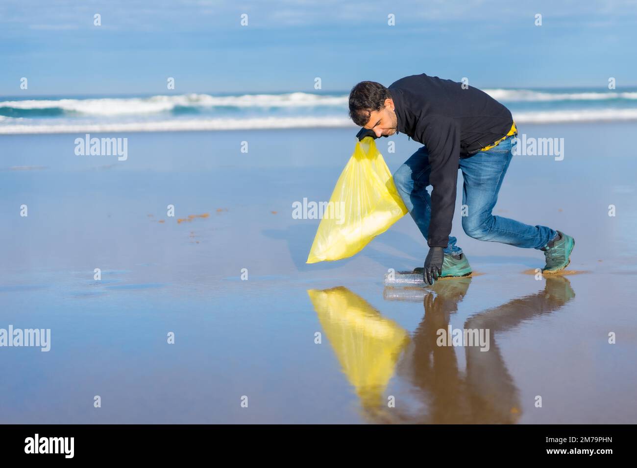 Mann, der Müll oder Plastik am Strand sammelt. Ökologiekonzept, Meeresverschmutzung Stockfoto