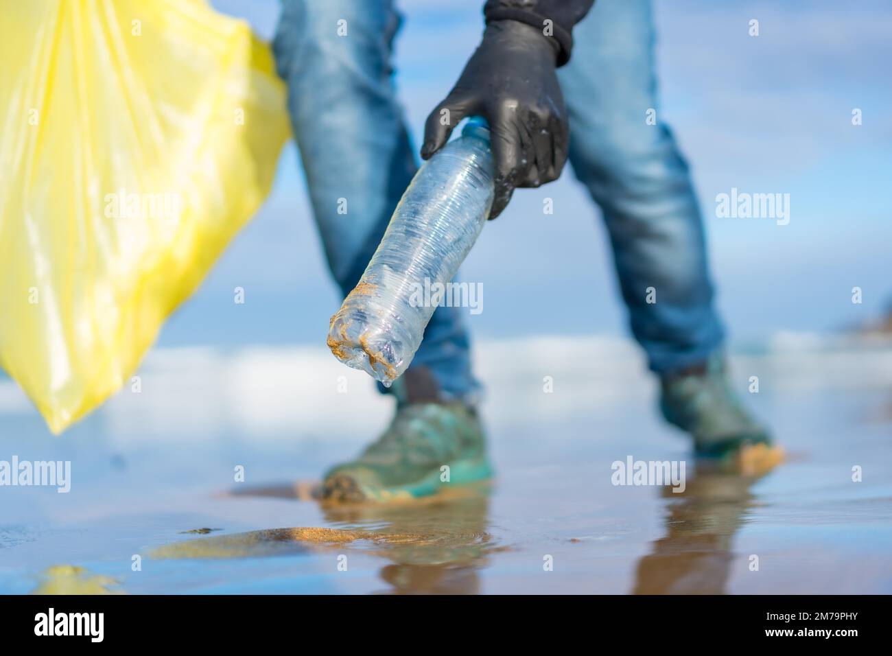 Meeresverschmutzung, nicht erkennbare Person, die Müll und Plastik am Strand sammelt. Ökologiekonzept Stockfoto