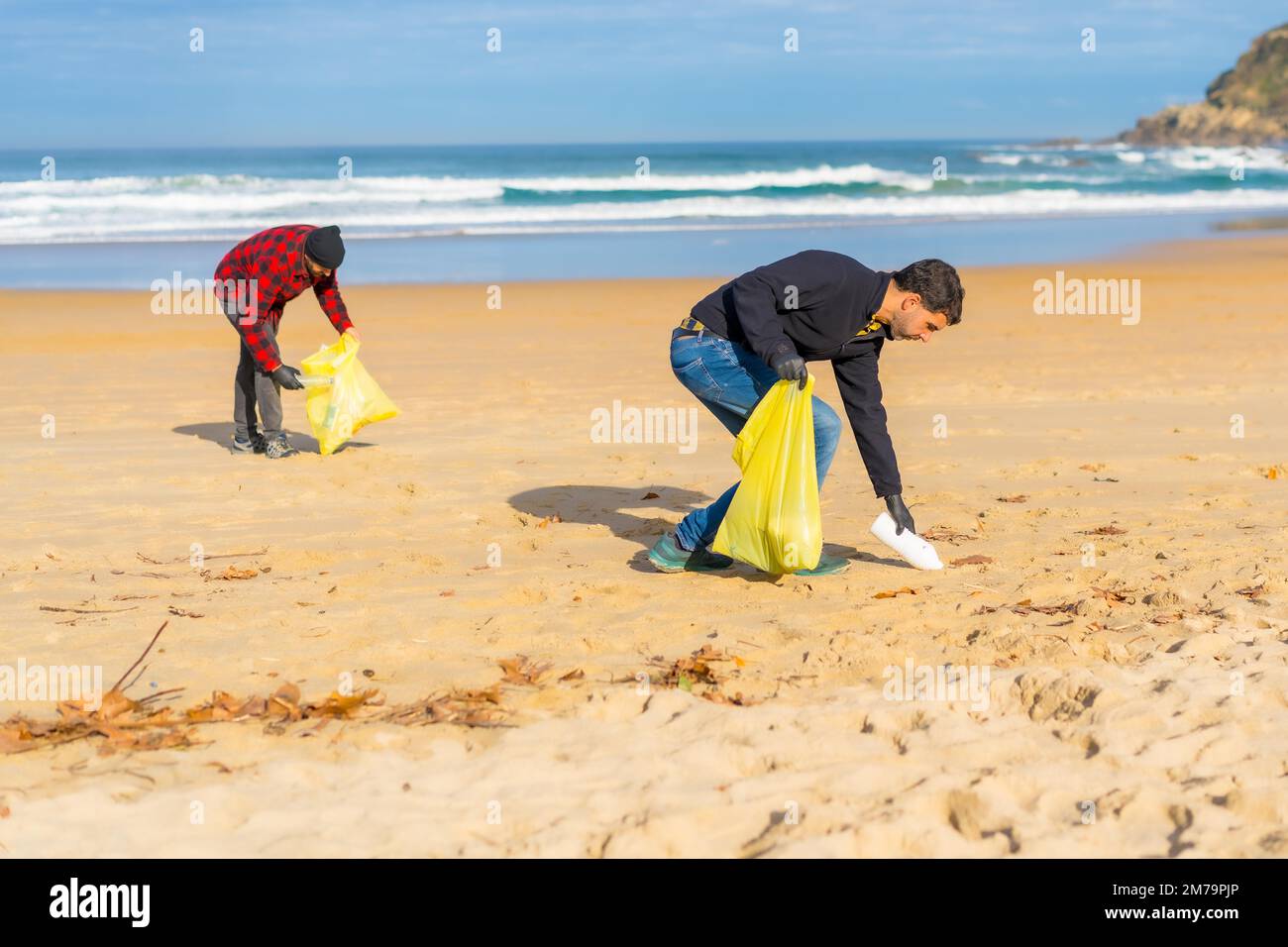 Freiwillige sammeln Plastik aus dem Sand am Strand. Ökologiekonzept, Meeresverschmutzung Stockfoto