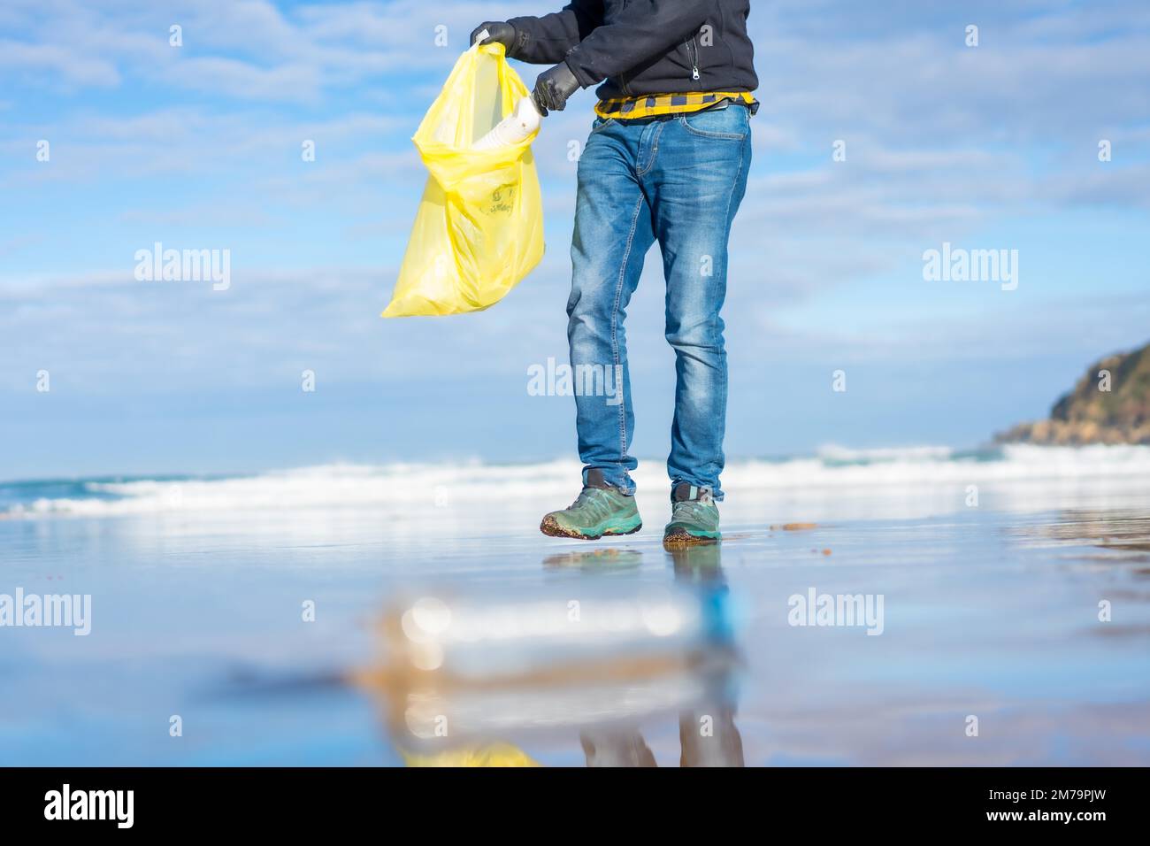 Meeresverschmutzung, nicht erkennbare Person, die Müll und Plastik am Strand sammelt. Ökologiekonzept Stockfoto