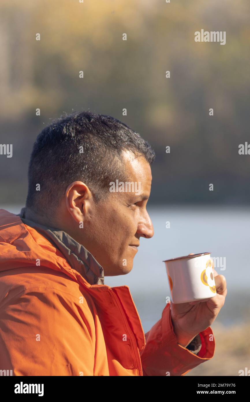 Porträt eines Reisenden am See im Herbst mit einer Tasse Kaffee. Hochwertiges Foto Stockfoto