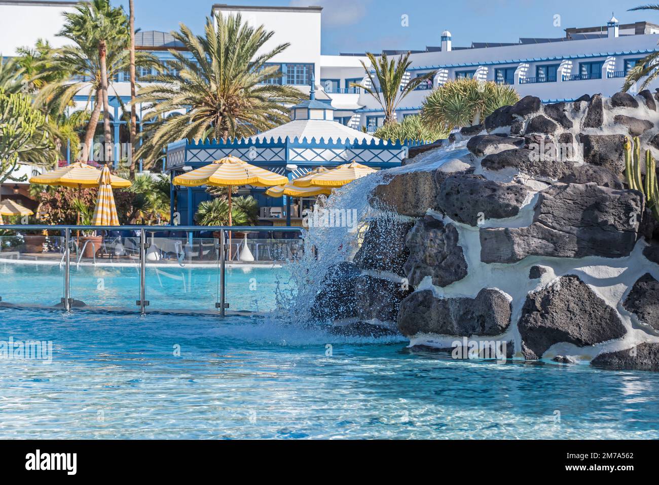 Puerto del Carmen, Spanien - 28. November 2022: Poollandschaft mit künstlichem Wasserfall, Sonnenschirmen und tropischen Pflanzen der Kanarischen Inseln Stockfoto