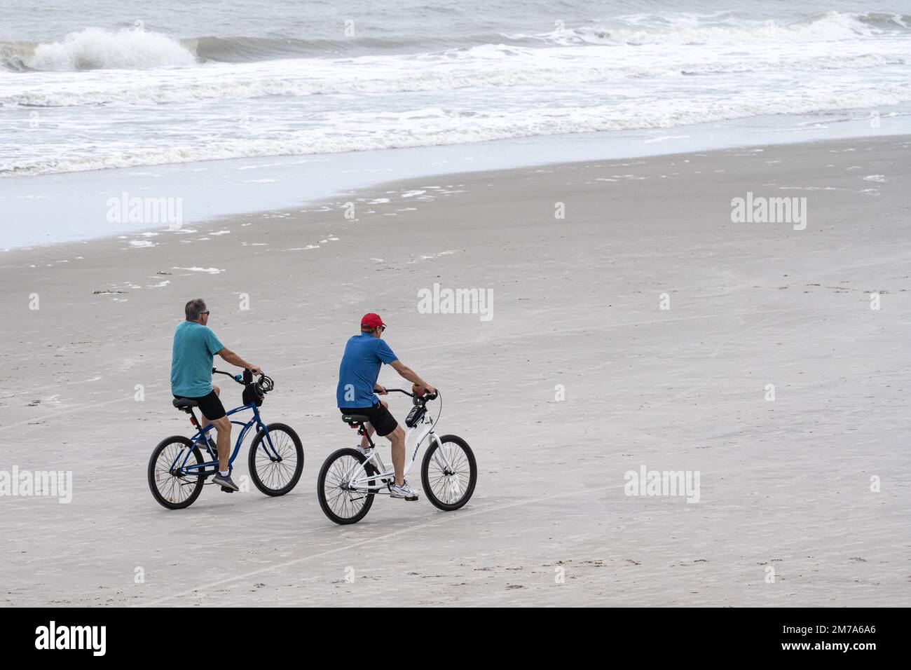 Ältere Männer, die am Jacksonville Beach im Nordosten Floridas mit dem Strandrad fahren. (USA) Stockfoto
