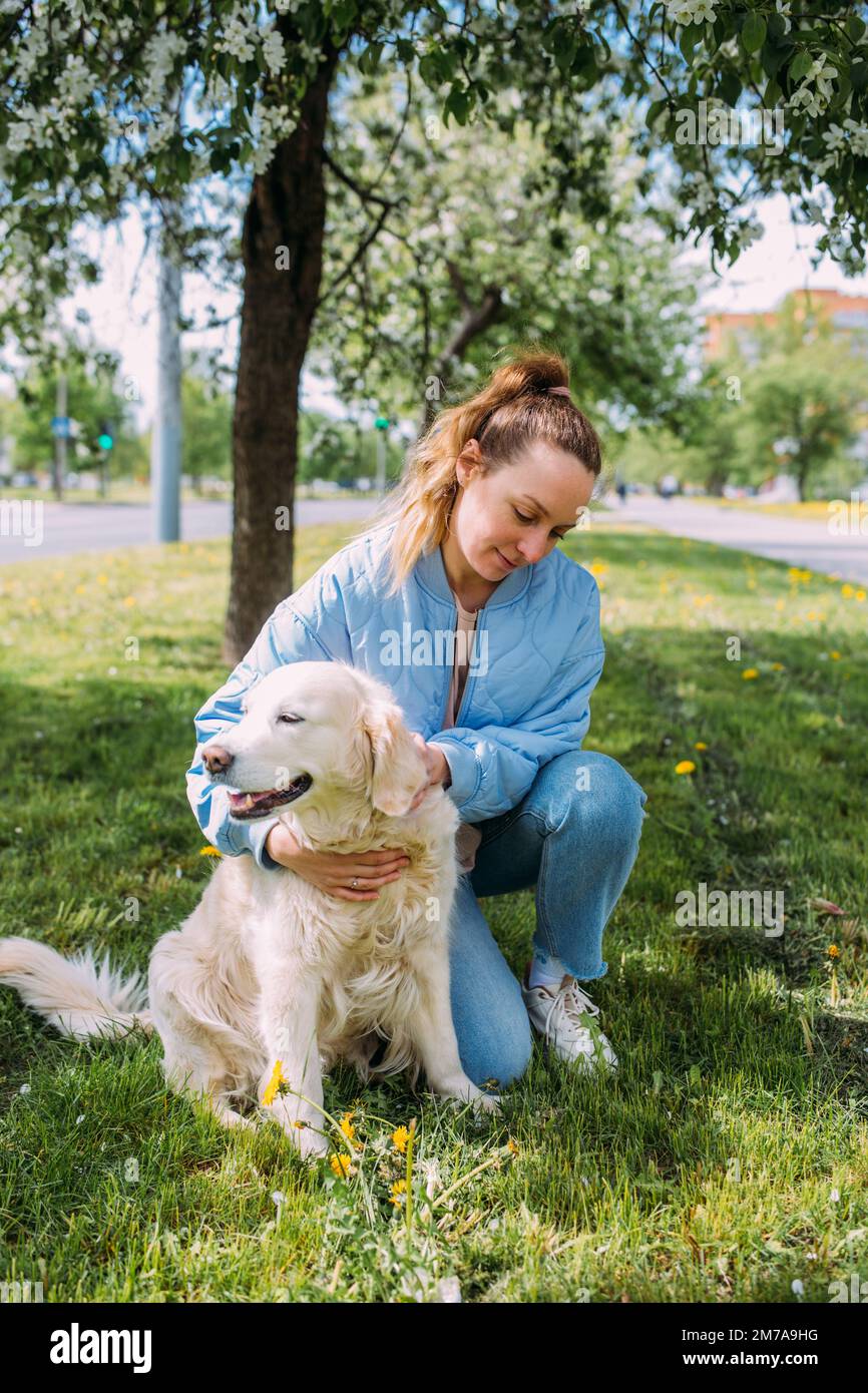 Junge schöne Frau und ihr goldener Retriever Hund haben Spaß im Frühjahr Stockfoto