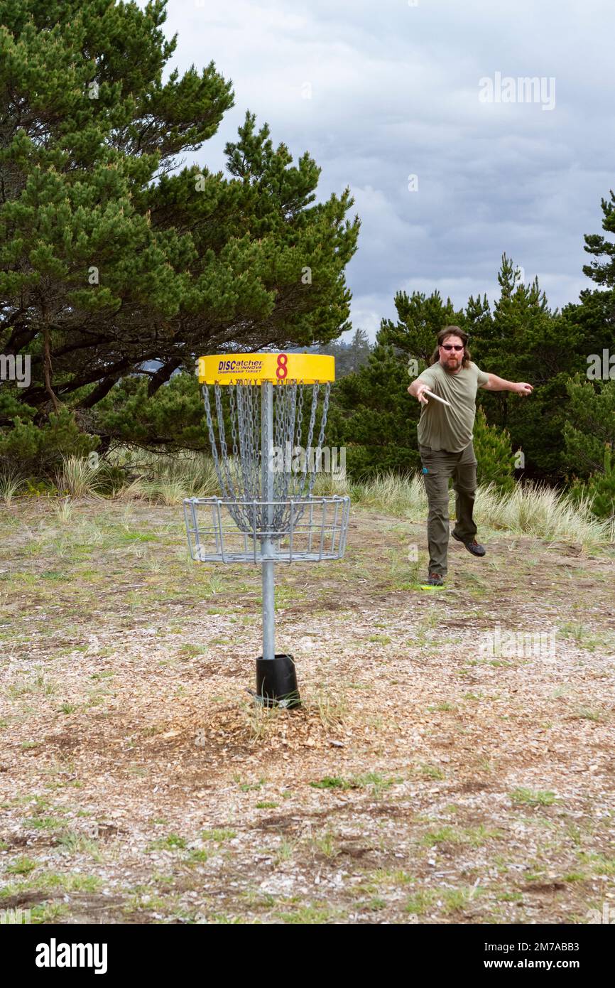 Ein Mann mit dunkler Sonnenbrille spielt Disc-Golf im South Beach State Park in Newport, Oregon, USA. Stockfoto