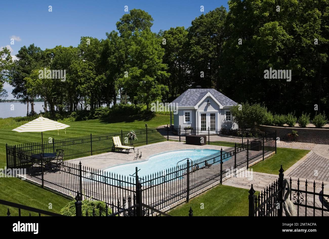 Im Sommer befindet sich ein Pool im Erdgeschoss, der von einem schwarzen schmiedeeisernen Zaun umgeben ist. Stockfoto