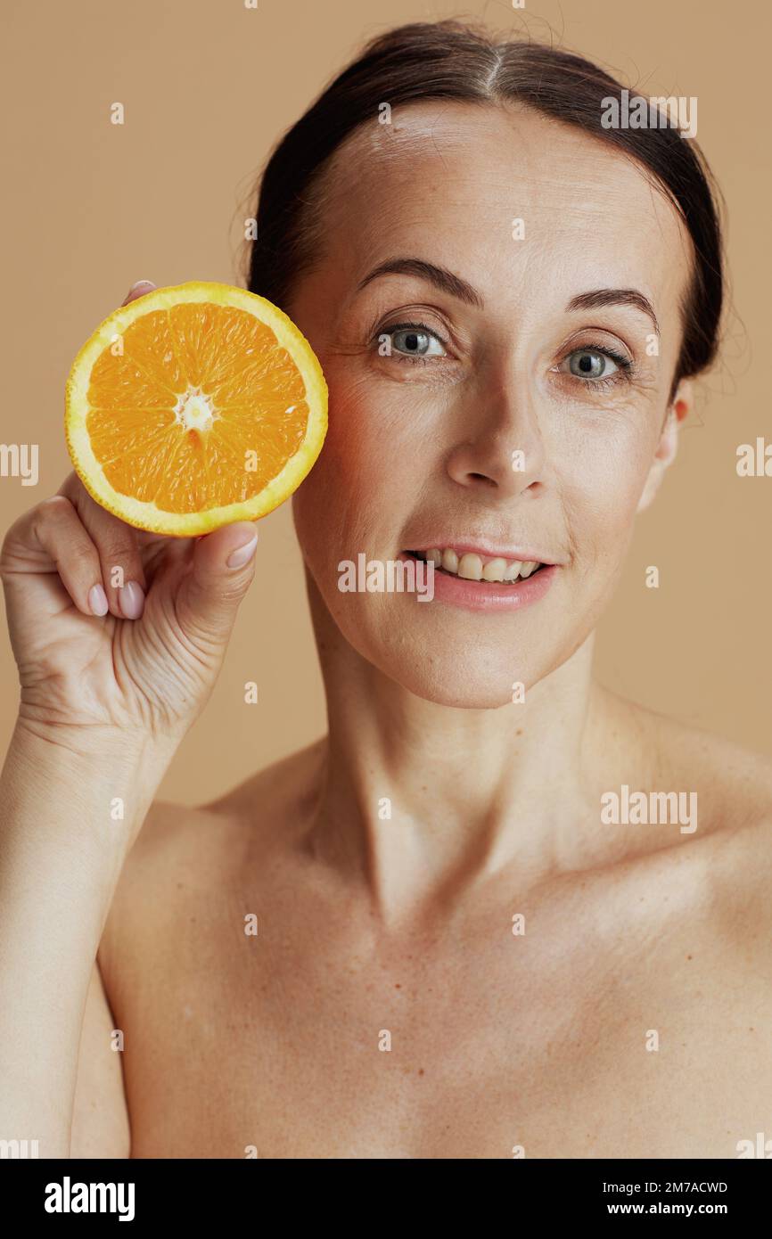 Porträt einer glücklichen, modernen 40-jährigen Frau mit Orange isoliert auf Beige. Stockfoto