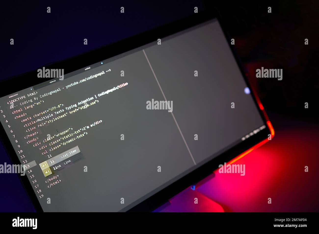 Schreib-Computercode wird auf dem Monitor angezeigt, Neonrot hinterleuchtet Stockfoto