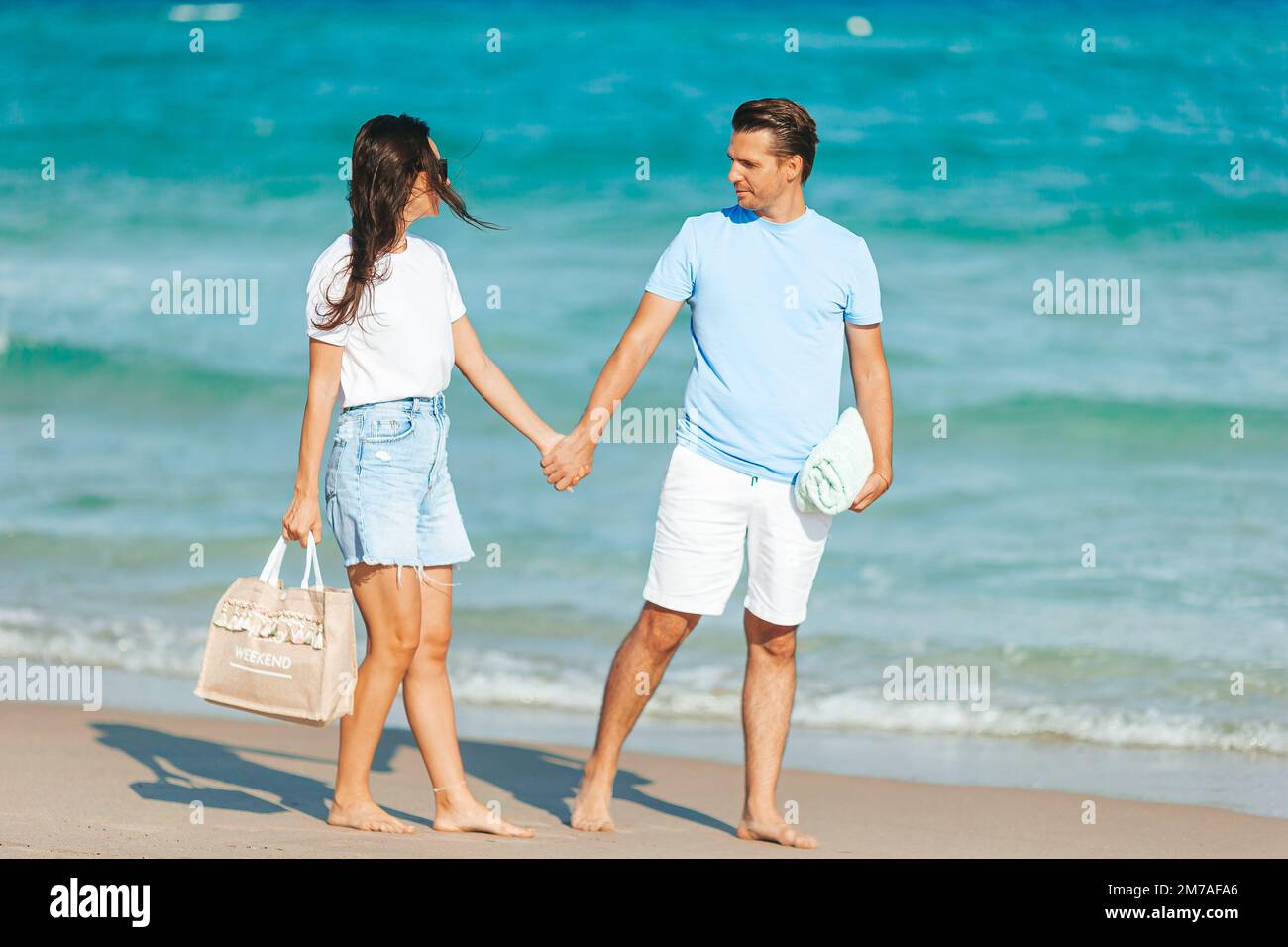 Ein junges Paar, das Händchen hielt, während er in den Strandferien spazierte Stockfoto