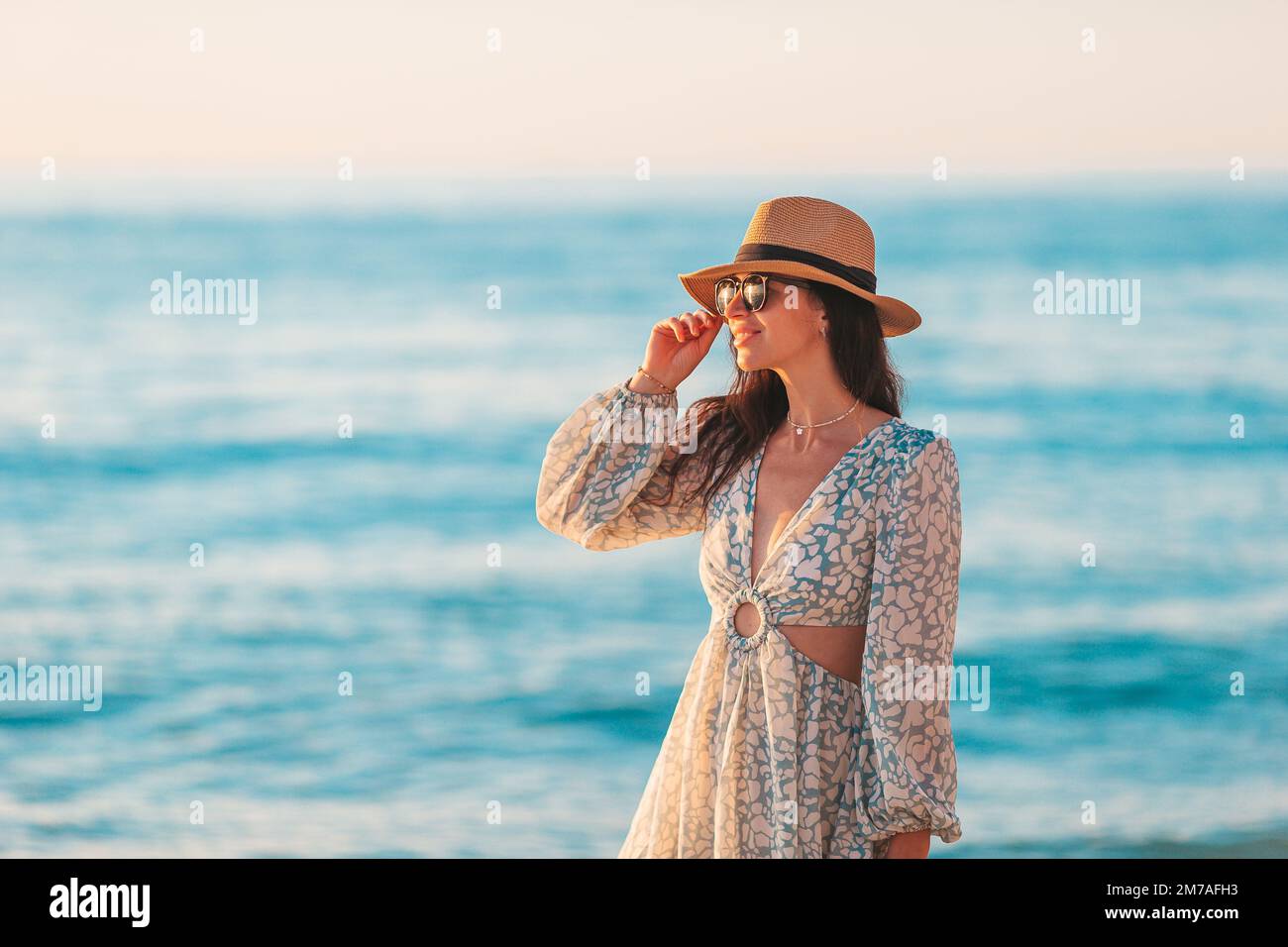 Junge glückliche Frau am Strand genießt ihren Sommerurlaub. Das Mädchen ist glücklich und ruhig in ihrem Aufenthalt am Strand Stockfoto