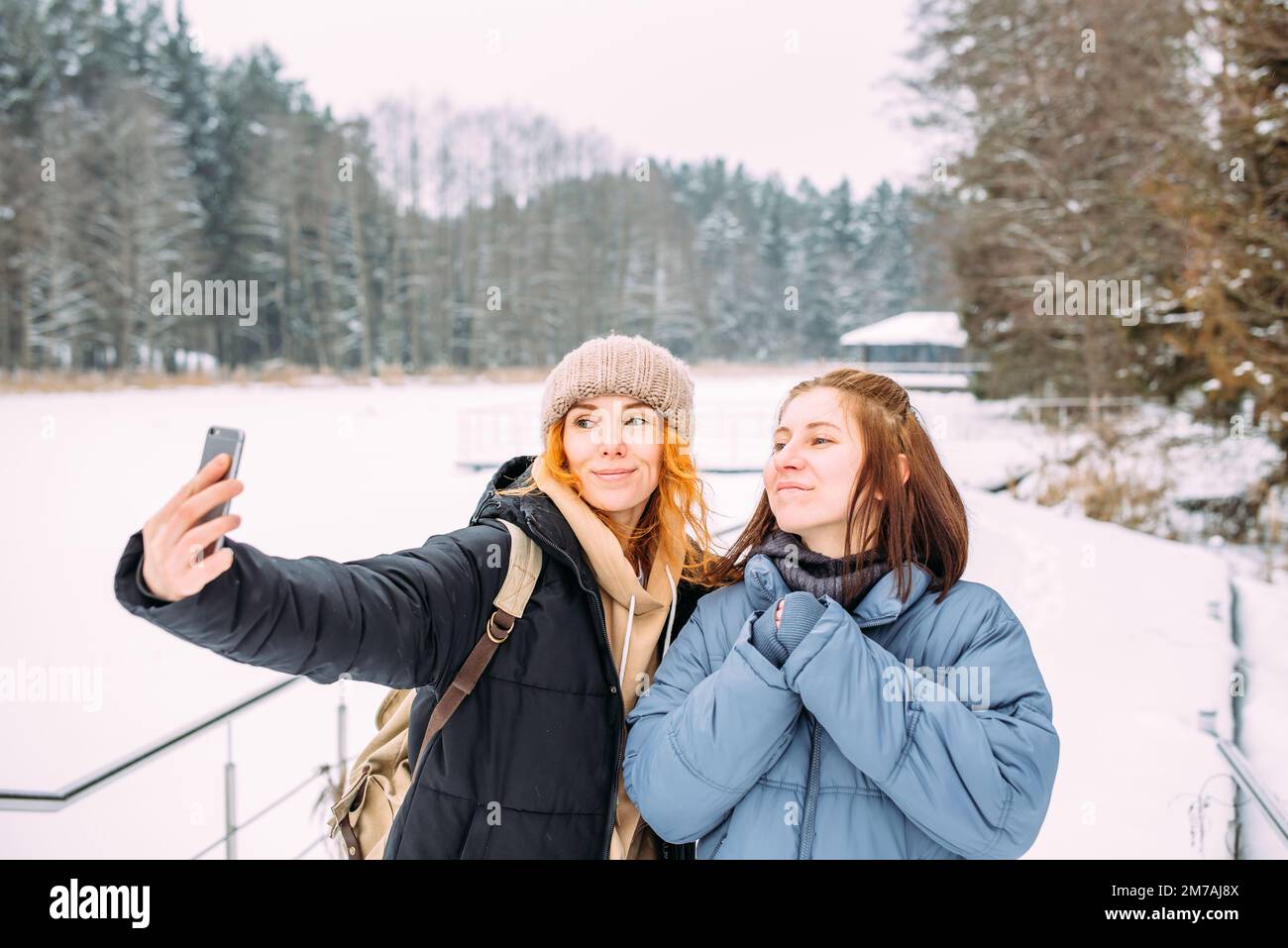 Zwei Frauen, die im Winter mit einem Telefon befreundet sind, machen im Winter ein Selfie Stockfoto