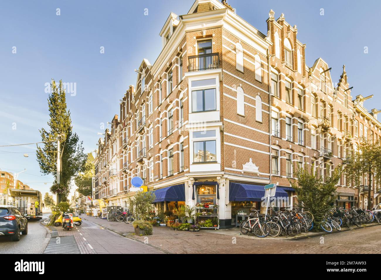 Eine Stadtstraße mit Gebäuden und Fahrrädern, die an der Seite der Straße vor einem Apartmenthaus geparkt sind Stockfoto