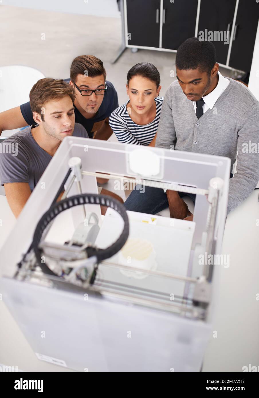 Fasziniert von moderner Technologie. Eine Gruppe von Designern, die sich einen 3D-Drucker ansehen. Stockfoto