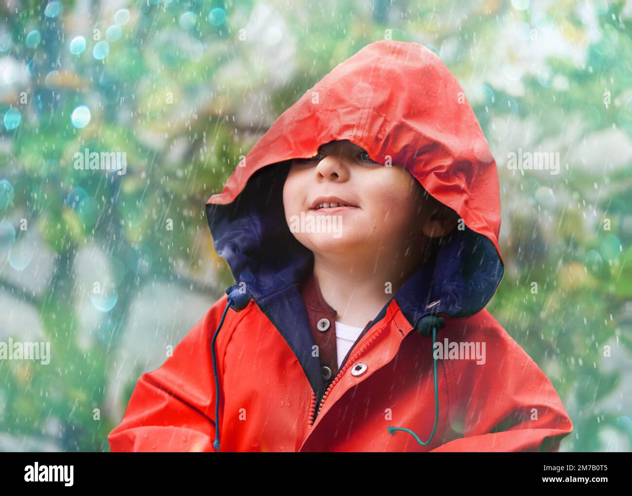 Keine Sonne, Kein Problem. Ein süßer kleiner Junge, der draußen im Regen spielt. Stockfoto
