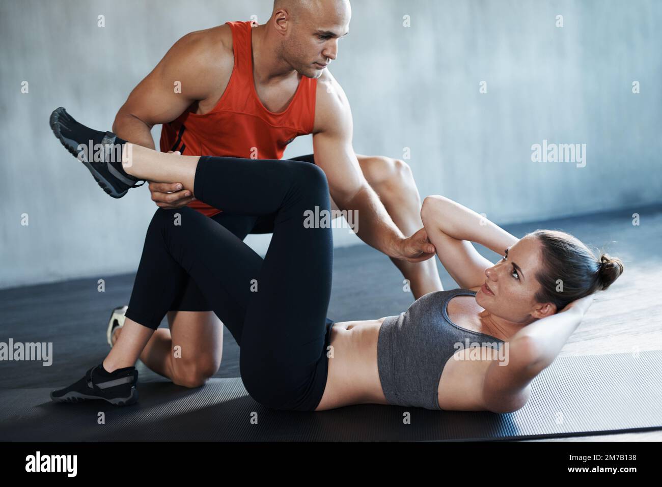 Trainieren, um kampffit zu werden. Ein Fitnesstrainer, der eine junge Frau in der Turnhalle trainiert. Stockfoto