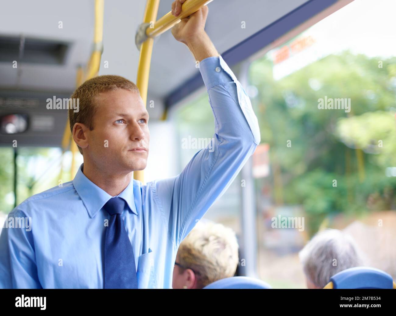 Geschäftsmann im Bus. Ein junger Geschäftsmann, der zur Arbeit pendelt. Stockfoto