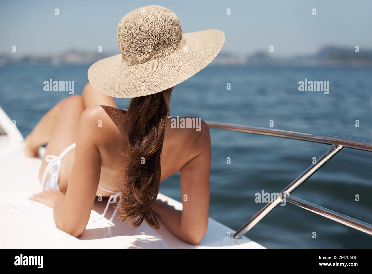 Urlaub im Luxus. Eine attraktive junge Frau, die sich auf dem Deck einer Luxusyacht bräunt. Stockfoto