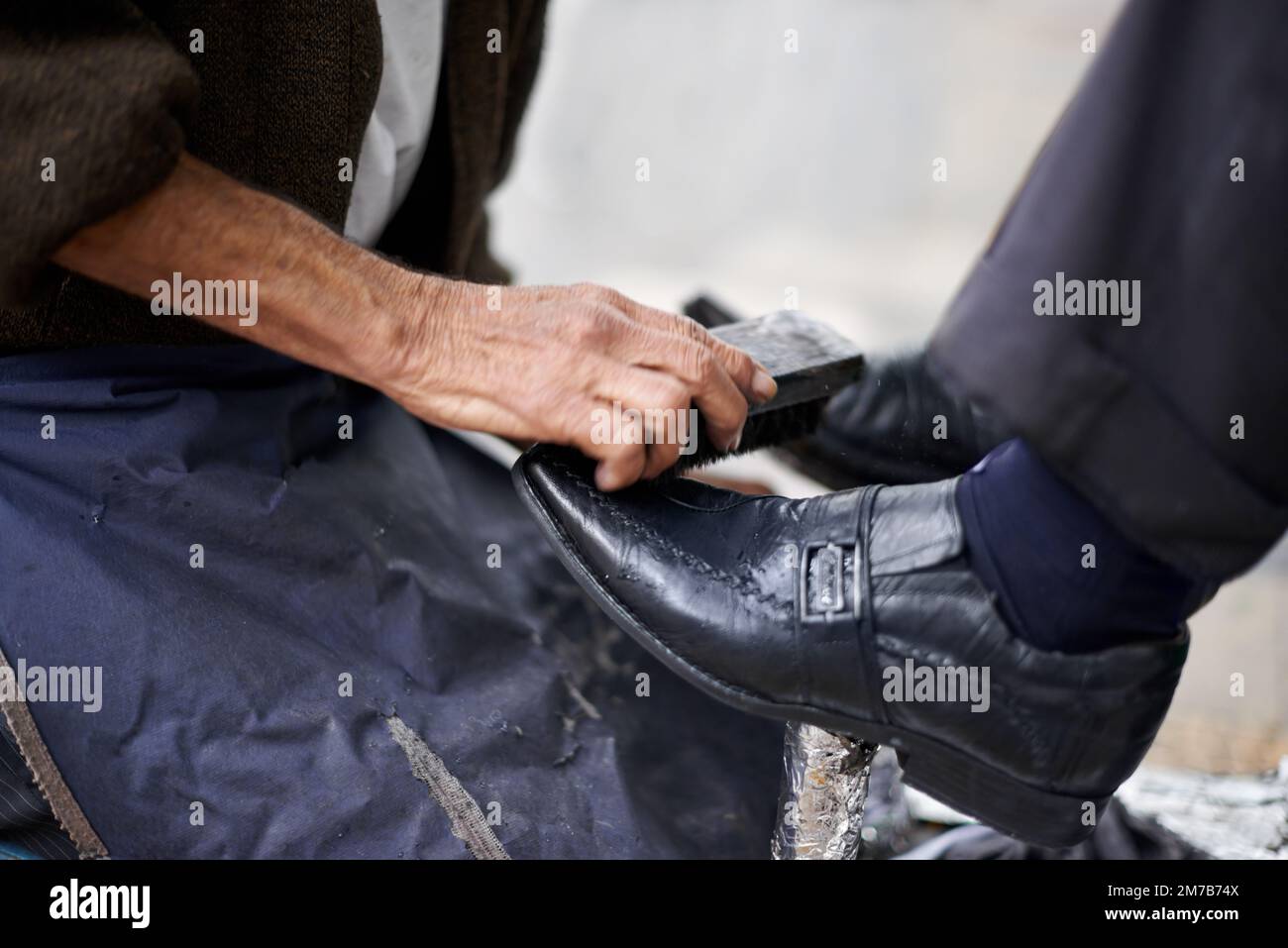 Die Schuhe polieren. Ein Schuhputzer, der die Schuhe eines Geschäftsmanns glänzt. Stockfoto