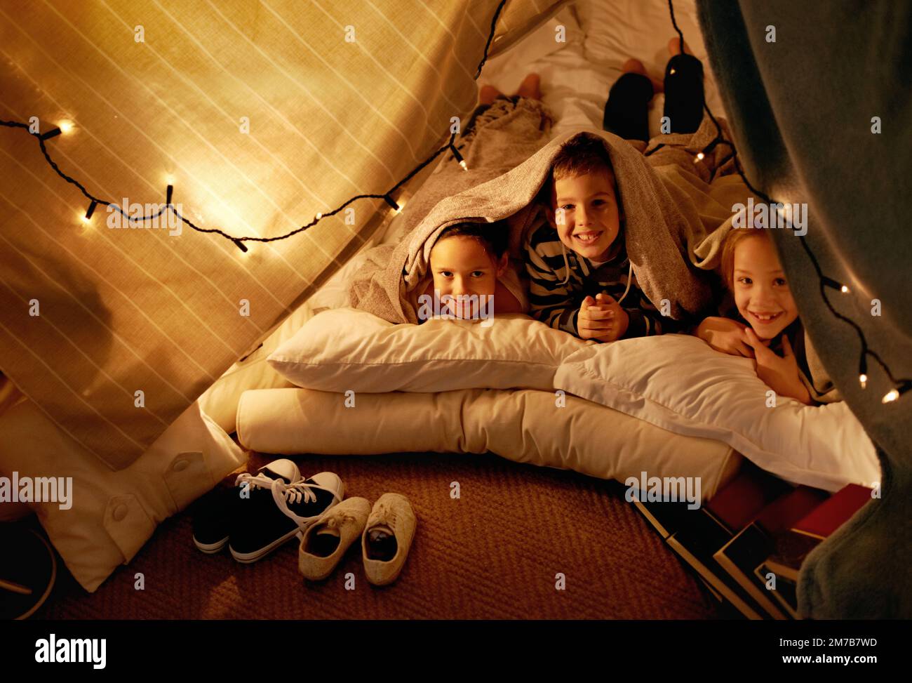 Wir haben eine aktive Fantasie. Drei kleine Kinder, die zusammen in einem Zelt spielen. Stockfoto