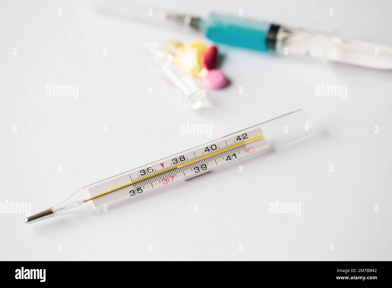 Thermometer und Pillen auf weißem Hintergrund, Nahaufnahme. Stockfoto