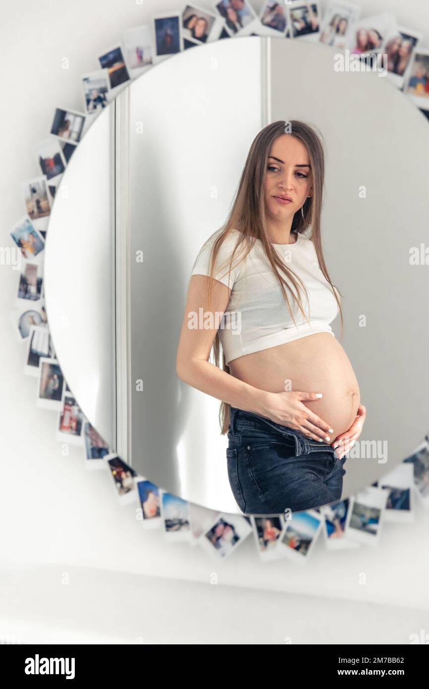 Attraktive junge Schwangere im Spiegel zu Hause. Stockfoto