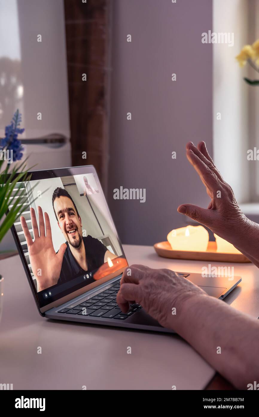 Eine alte Frau kommuniziert mit ihrem Sohn über eine Videoverbindung über einen Laptop. Stockfoto