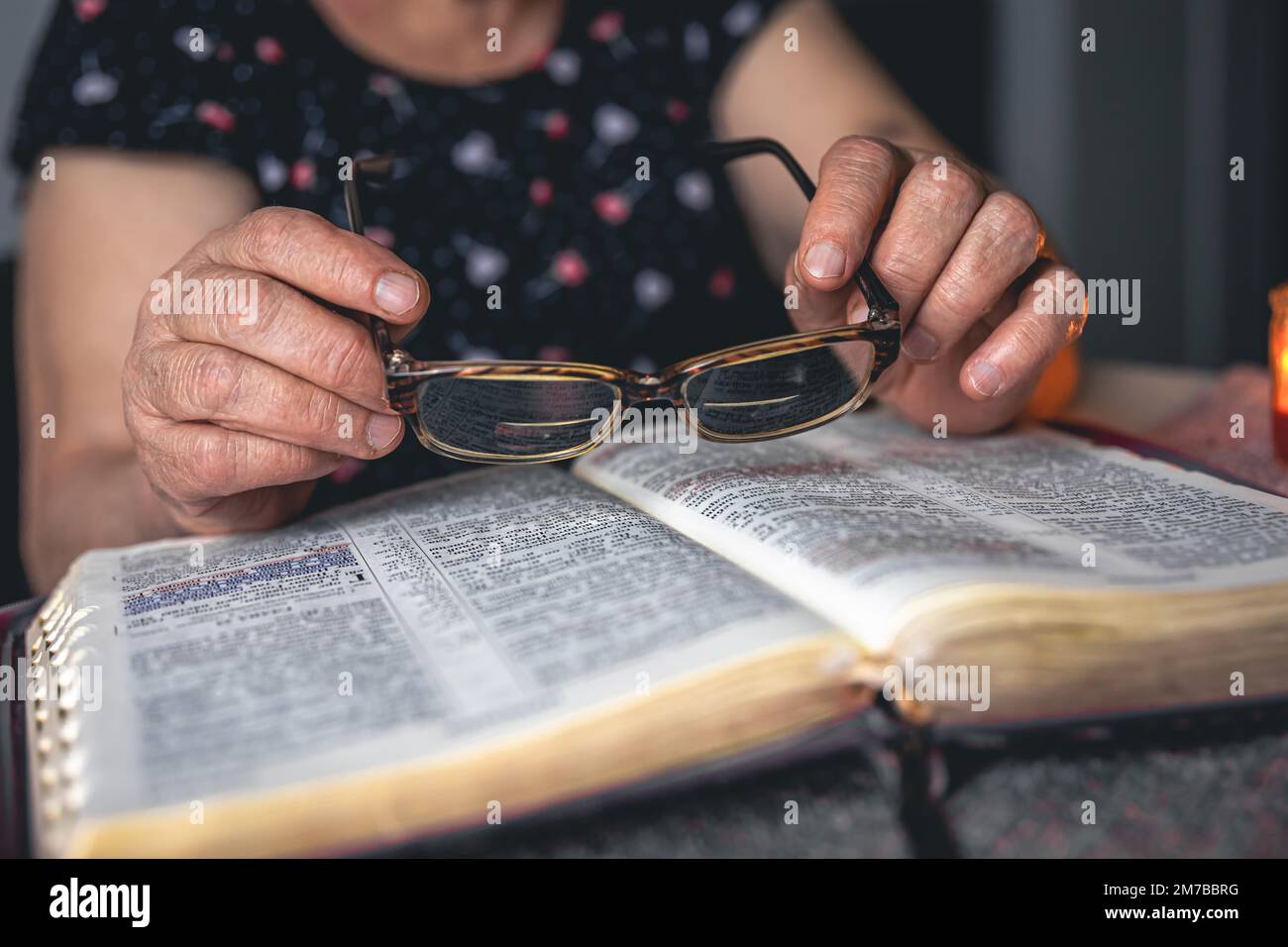 Eine alte Frau liest die Bibel, die Hände sind dicht. Stockfoto