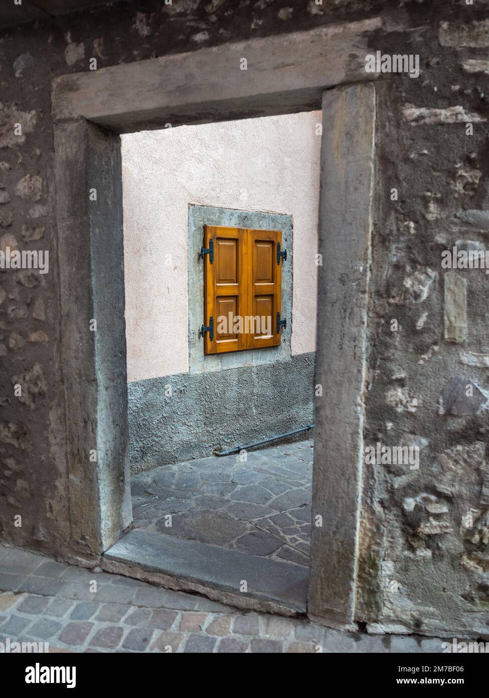 Blick durch den Innenhof zu einem geschlossenen Fenster eines traditionellen Hauses im Dorf Sutrio, Italien Stockfoto