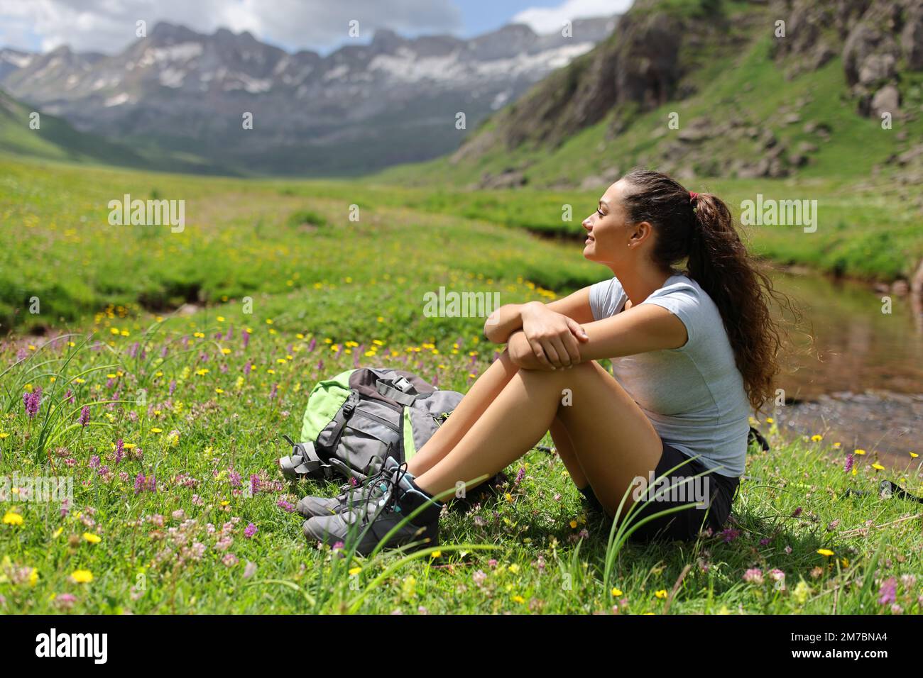 Wanderer mit Bergblick in einem Grün in einem Tal am Flussufer Stockfoto