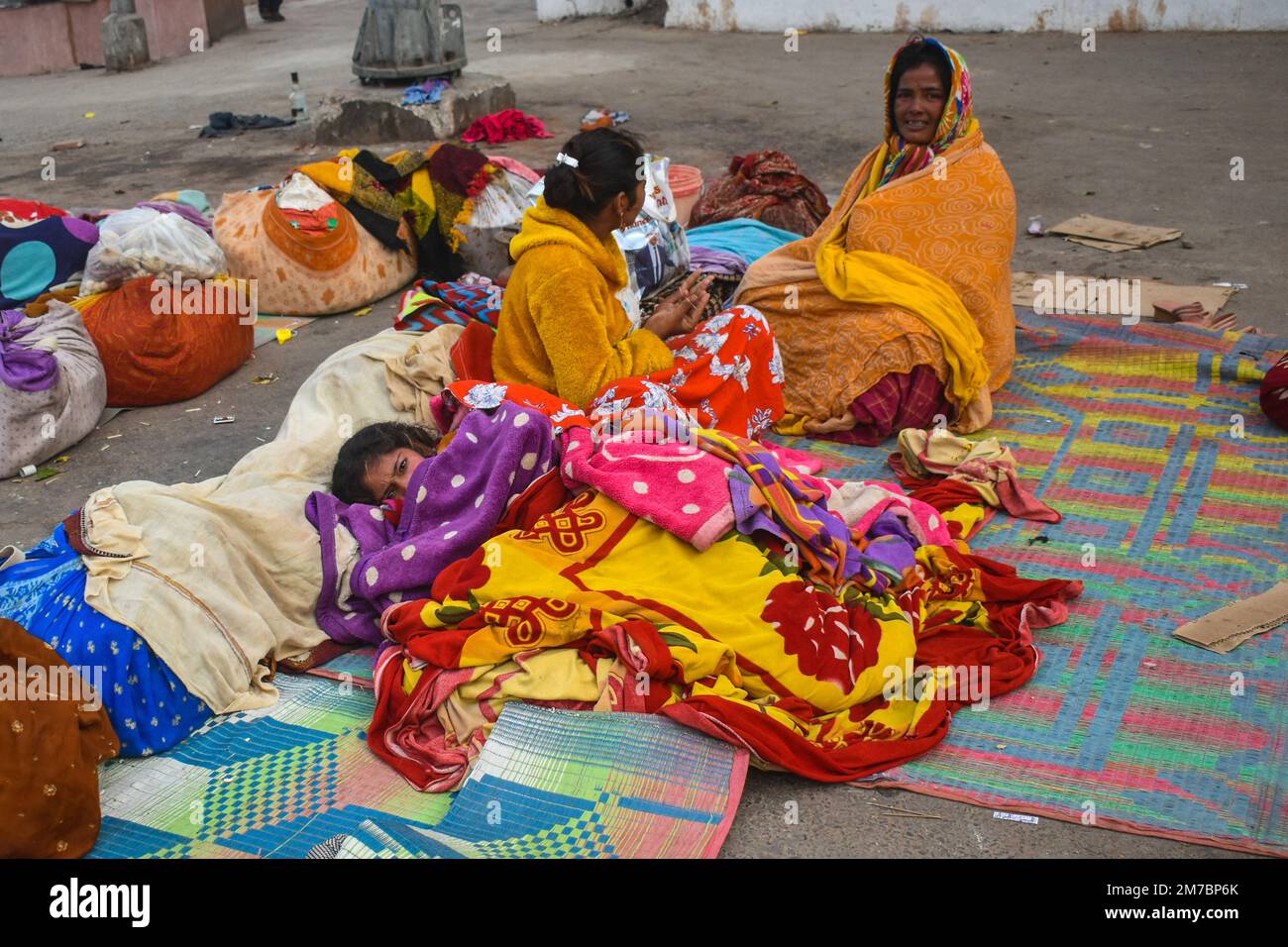 Menschen, die in Decken eingewickelt sind, schlafen an einem kalten Wintermorgen in Kalkutta am Straßenrand. Stockfoto