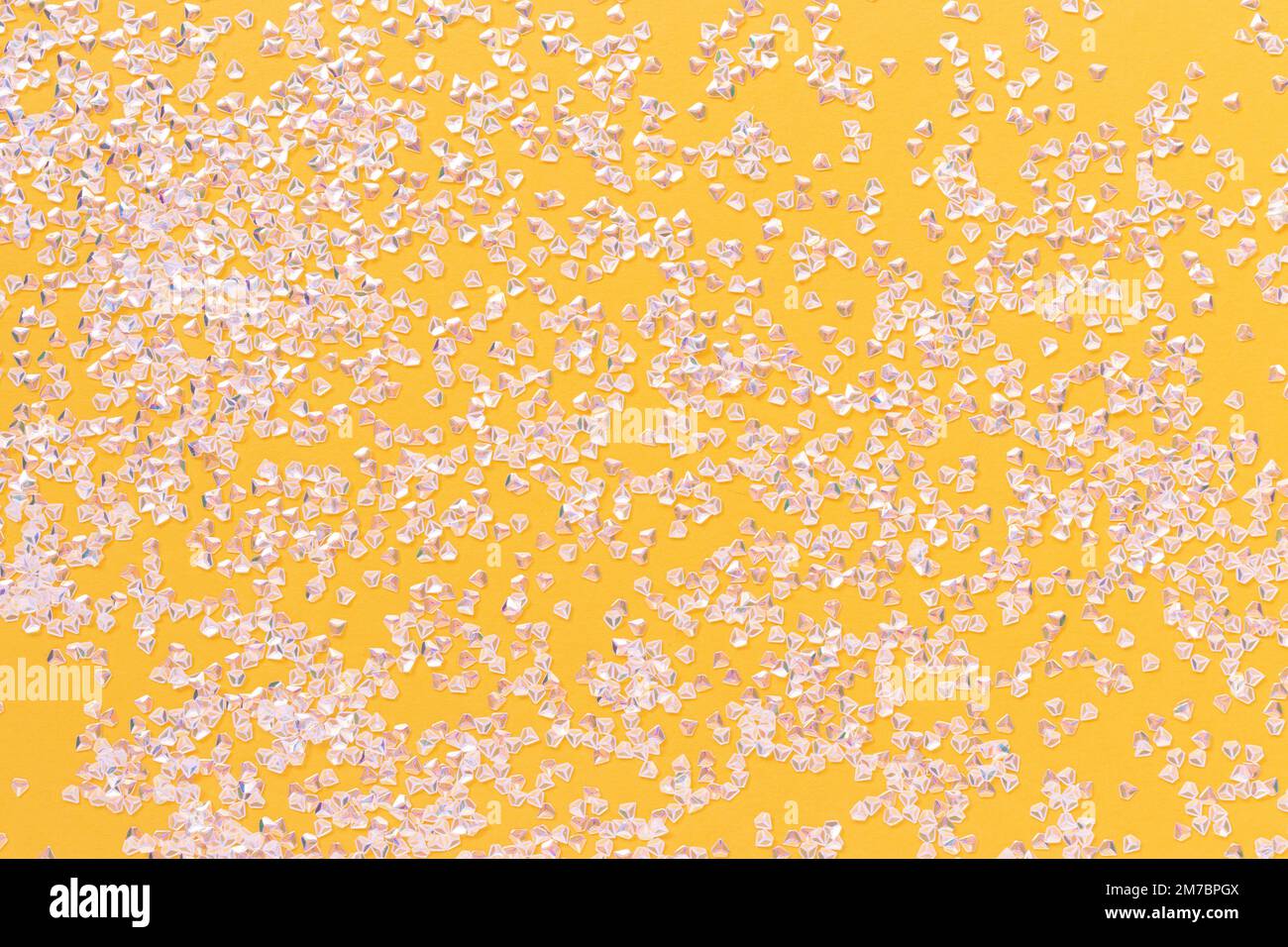 Kleine silberne Kristallkonfetti auf hellgelbem Hintergrund. Glitzernde Textur. Stockfoto