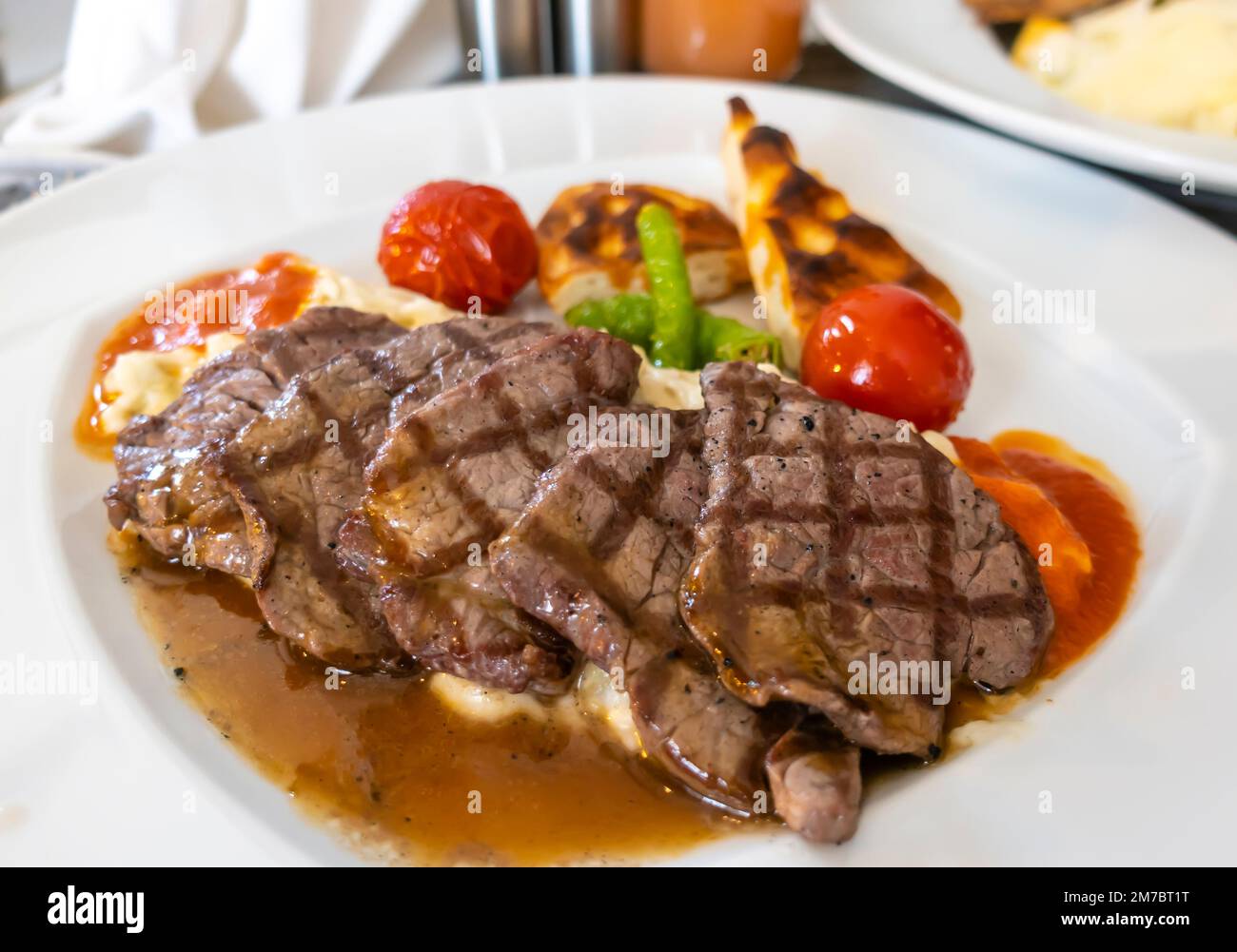 Kalbsbraten auf einem Teller. Kalbsschnitzel Rinderfilet, geröstete Tomaten auf Auberginen, Pita-Brot mit Pfefferbutter, Thymian-Sauce. Aruni Ankara Stockfoto