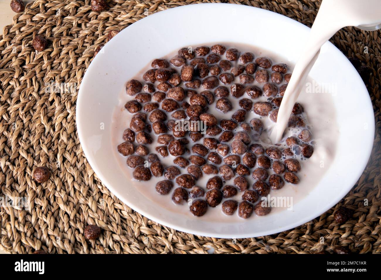 Schokoladenkugeln in einer weißen runden Platte gießen Sie die Milch darüber Stockfoto