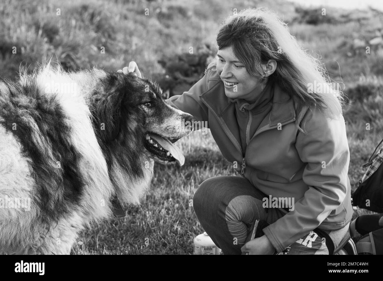Glückliche Frau streichelt karpaten Hirtenhund monochrome landschaftliche Fotografie Stockfoto