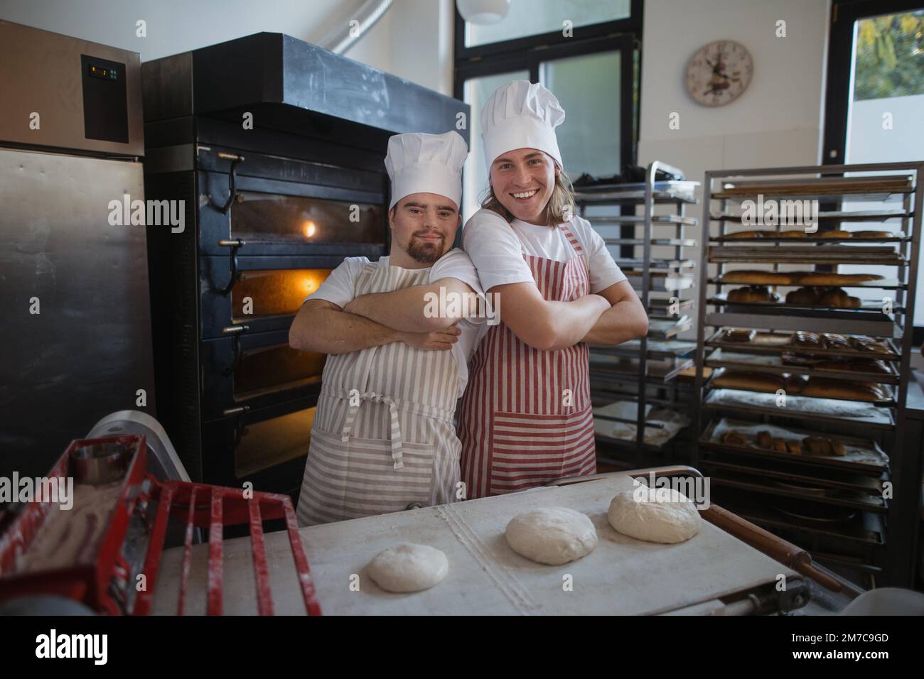 Porträt eines Mannes mit Down syndrom und seines Kollegen in der Bäckerei. Konzept der Integration von Menschen mit Behinderungen in die Gesellschaft. Stockfoto