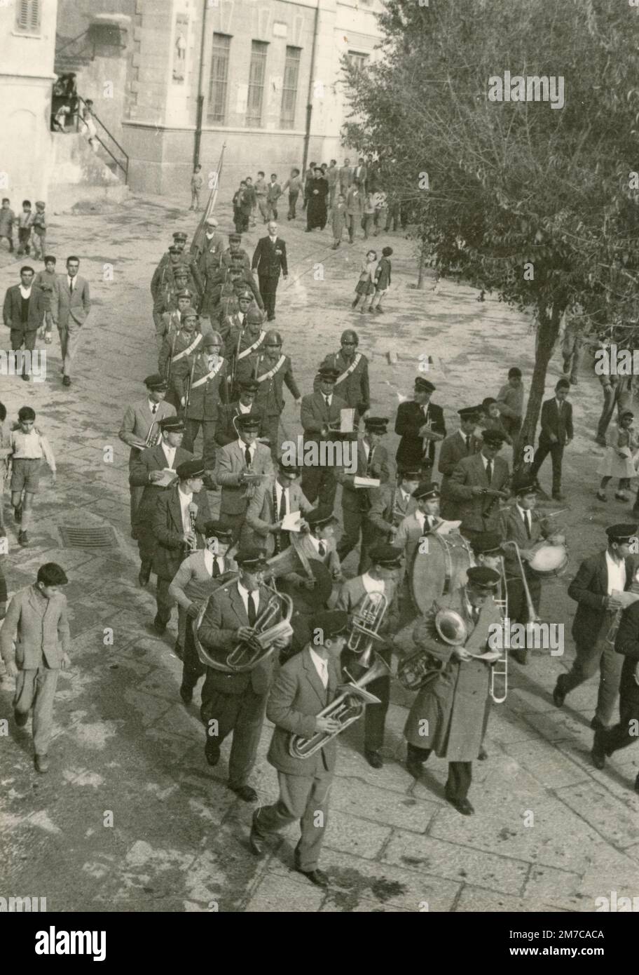 Musikband, die an der Straße des kleinen Dorfes, Italien 1950er vorbeizieht Stockfoto