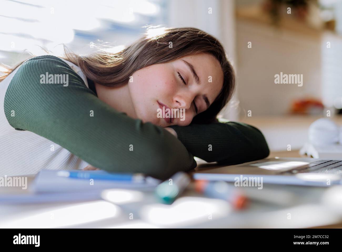 Junge Frau schläft während des Lernens an einem Tisch ein. Stockfoto