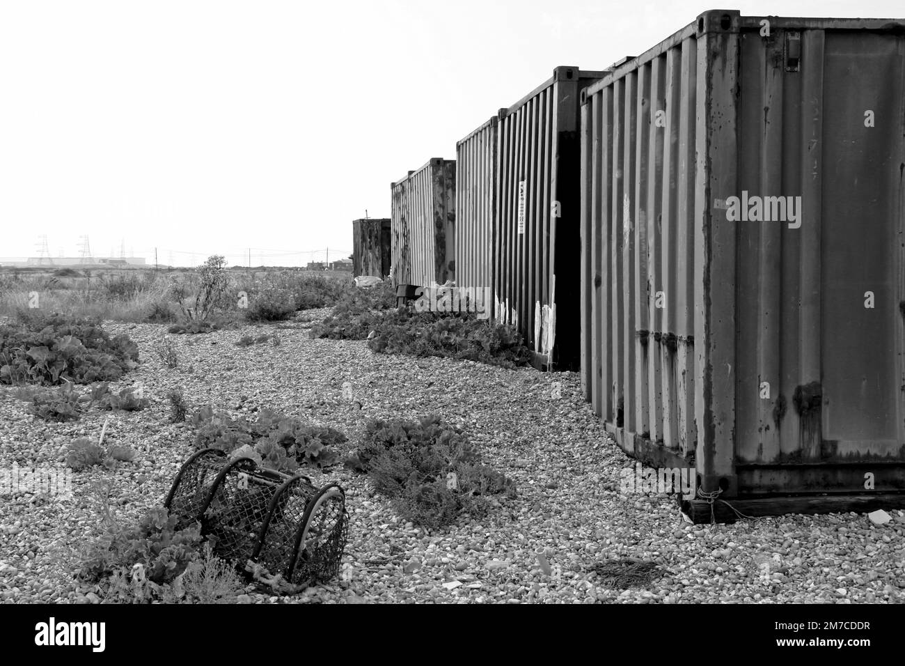 Schwarzweißbild alter Metallbehälter und verlassenes Fischkrebse am Dungeness Beach Kent Stockfoto