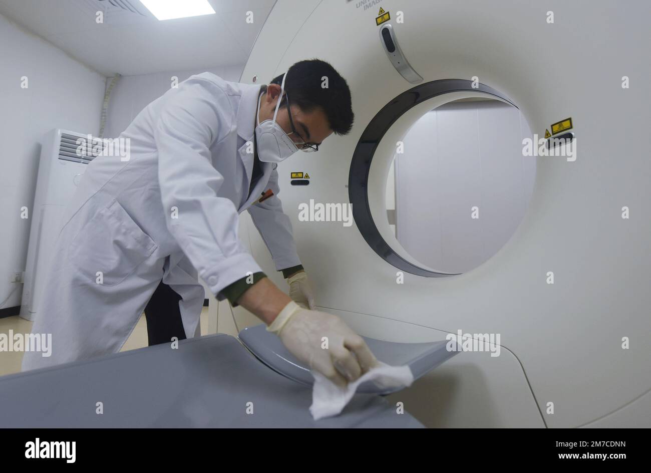 HANGZHOU, CHINA - 9. JANUAR 2023 - Ein Radiologe an einem Gemeindegesundheitsdienst-Zentrum desinfiziert den Ort, an dem Menschen auf dem Rücken liegen, mit Alkohol Stockfoto