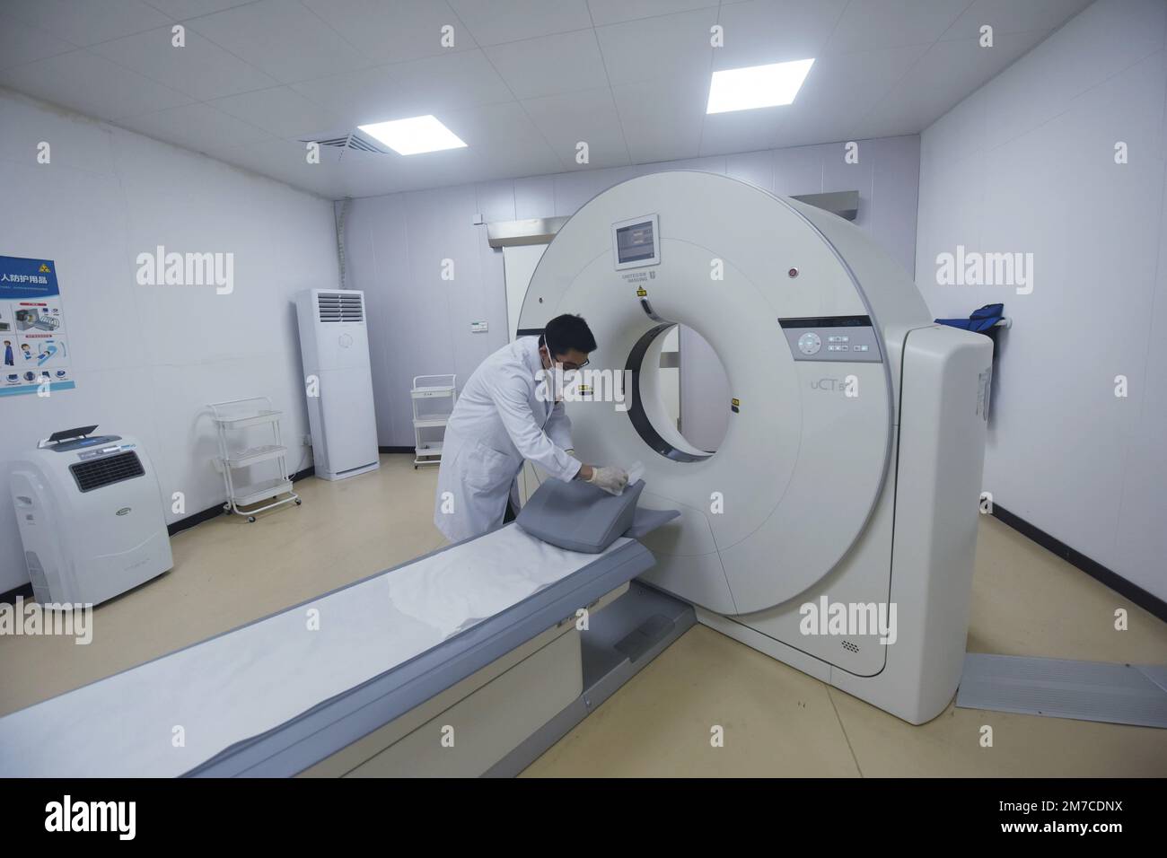 HANGZHOU, CHINA - 9. JANUAR 2023 - Ein Radiologe an einem Gemeindegesundheitsdienst-Zentrum desinfiziert den Ort, an dem Menschen auf dem Rücken liegen, mit Alkohol Stockfoto