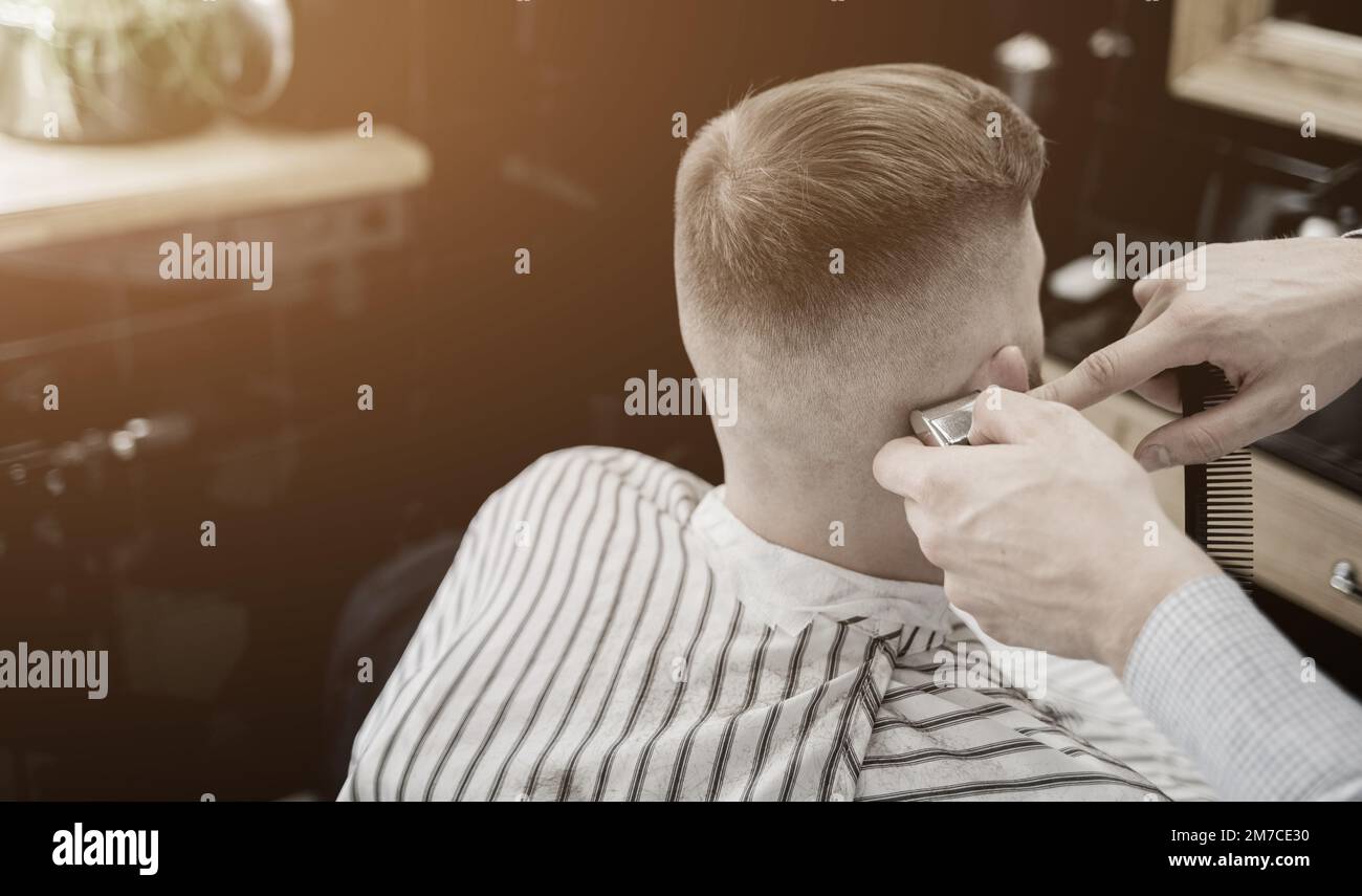 Friseuse Männer Barbershop. Herren Barbiere. Barber schneidet die Kundenmaschine für Haarschnitte. Stockfoto