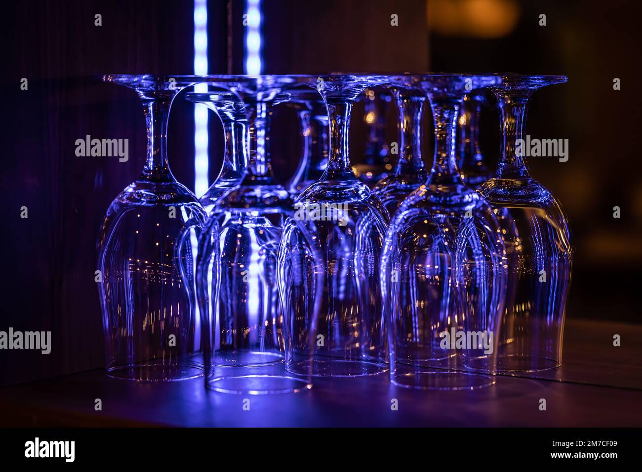 Saubere Weingläser in der Nachtbar, die in Neonfarben leuchten. Stockfoto