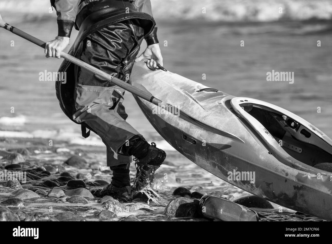 Kajakfahrer, der sein Boot am Ufer entlang zieht Stockfoto