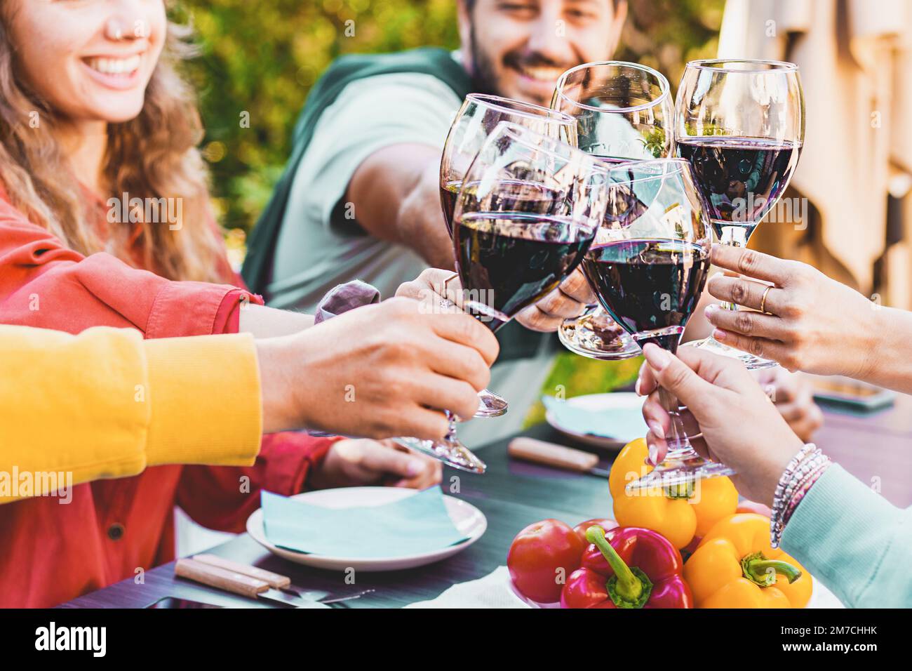 Vielfältige Gruppe von Freunden, die Rotweingläser während der Feier anstoßen während der Dinnerparty im Sommer im Freien - Menschen, Freundschaft und Alkohol Stockfoto