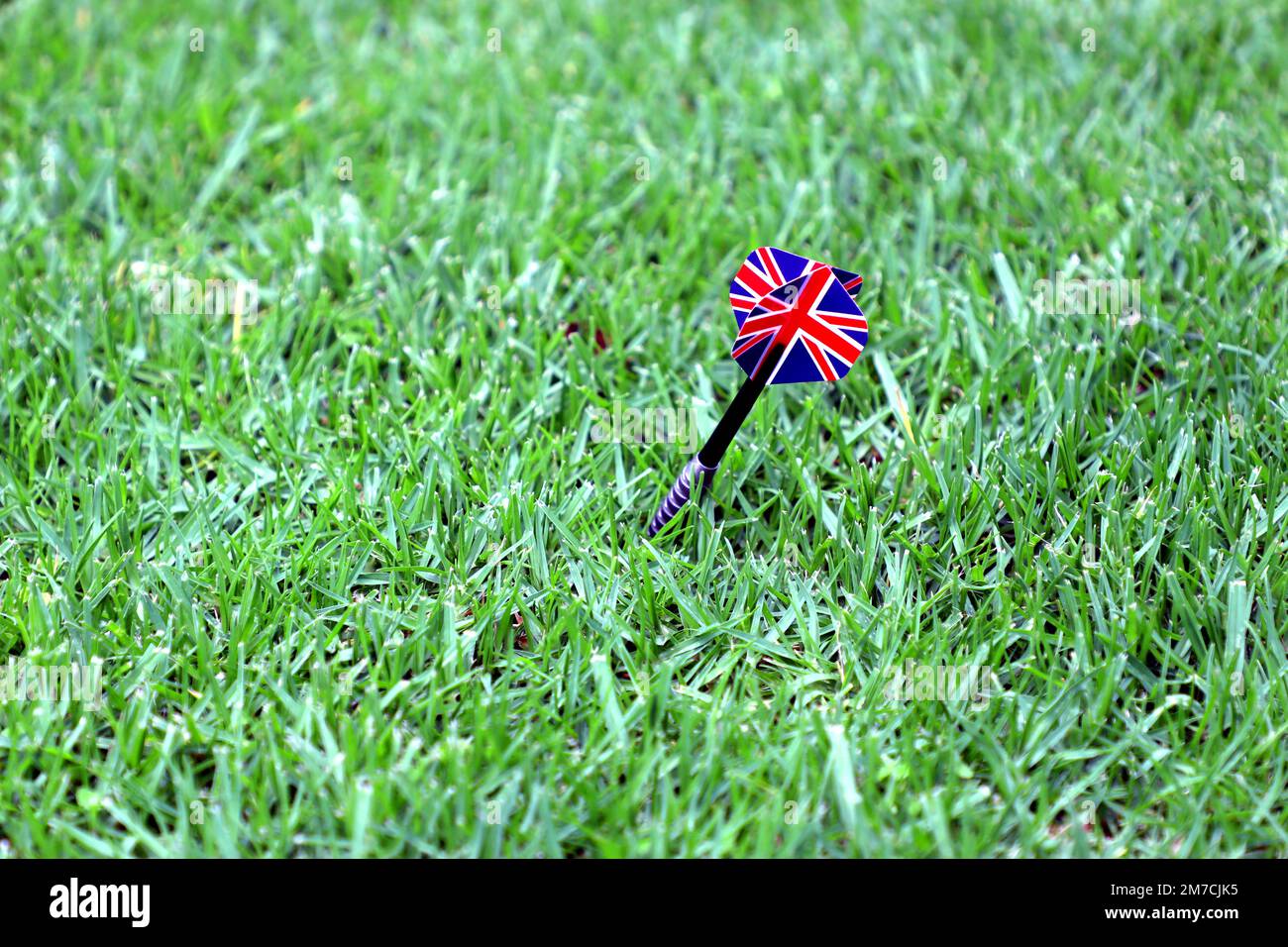 Ein Pfeil ohne Dartscheibe, der im Gras feststeckt, mit einer britischen Flagge und einem Kopierraum Stockfoto