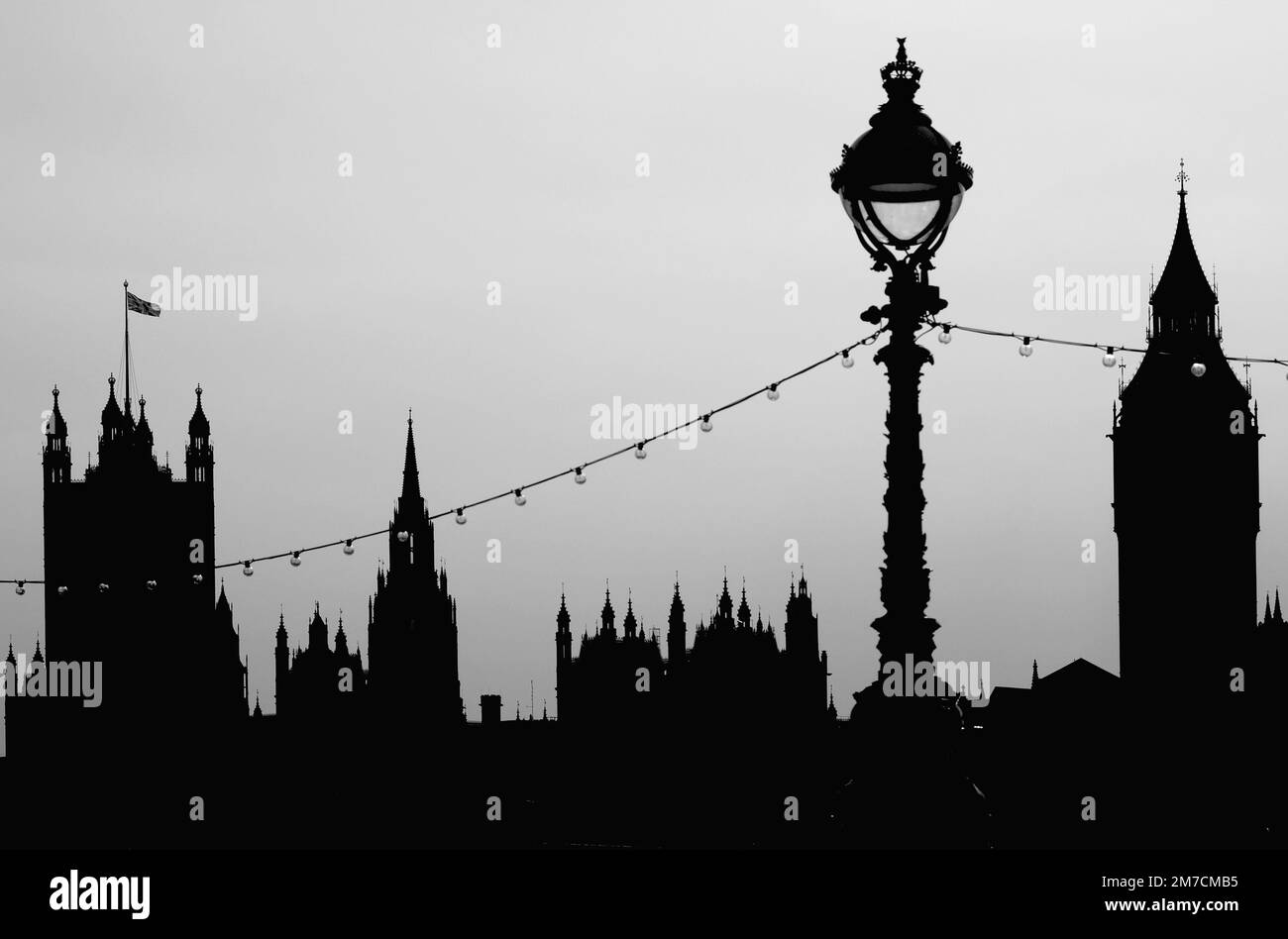 Die Silhouette des Westminster Palace, London UK, in Monochrom, mit Lampenpfosten, vom South Bank aus gesehen Stockfoto