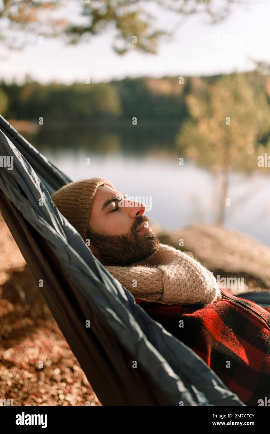 Ein Mann mit Bart ruht mit geschlossenen Augen in einer Hängematte Stockfoto